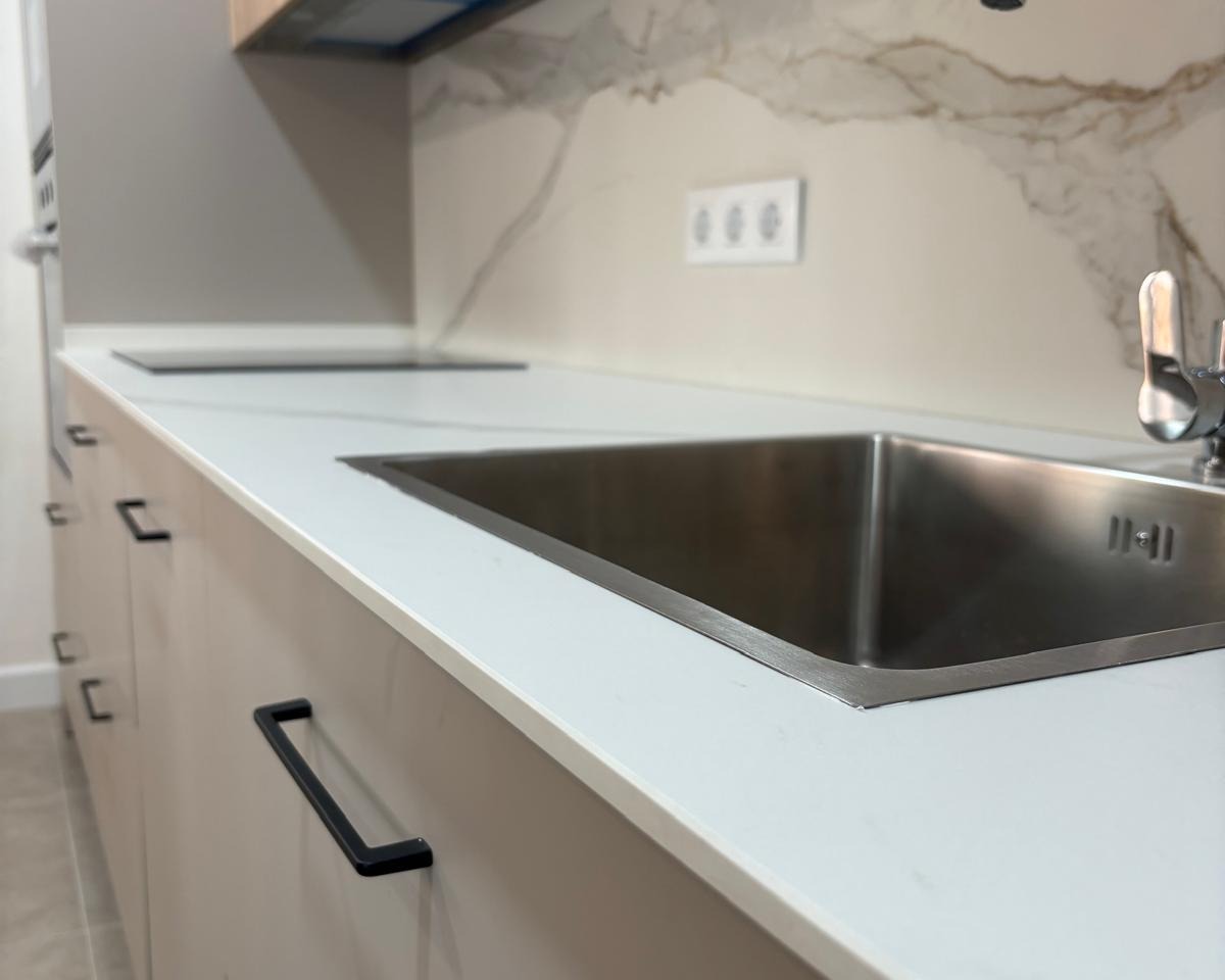 Fregadero negro sobre encimera con grifo moderno y rejilla